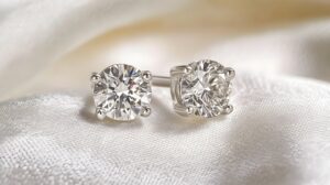 A pair of white gold stud earrings with round diamonds, set neatly on a pristine white surface